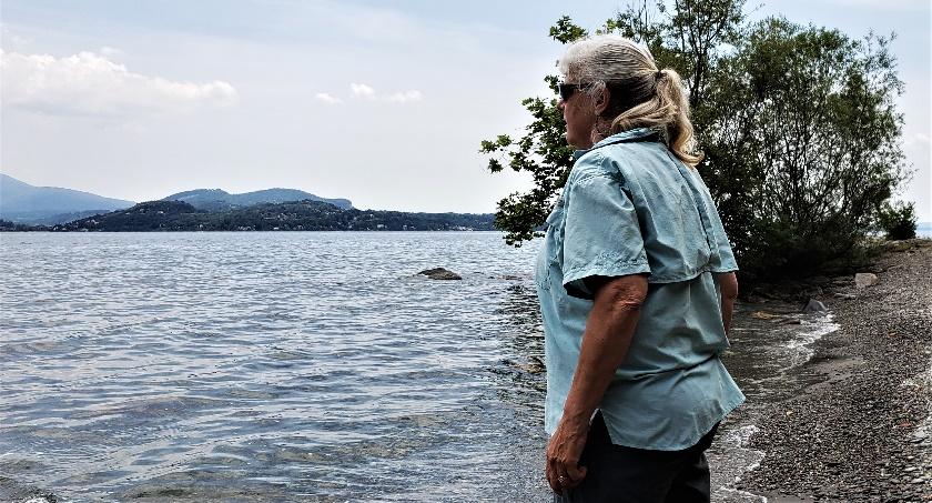 A person standing next to a lakeDescription automatically generated