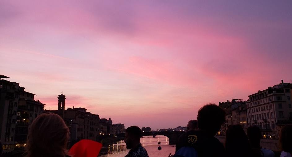 A group of people standing in front of a pink skyDescription automatically generated with low confidence