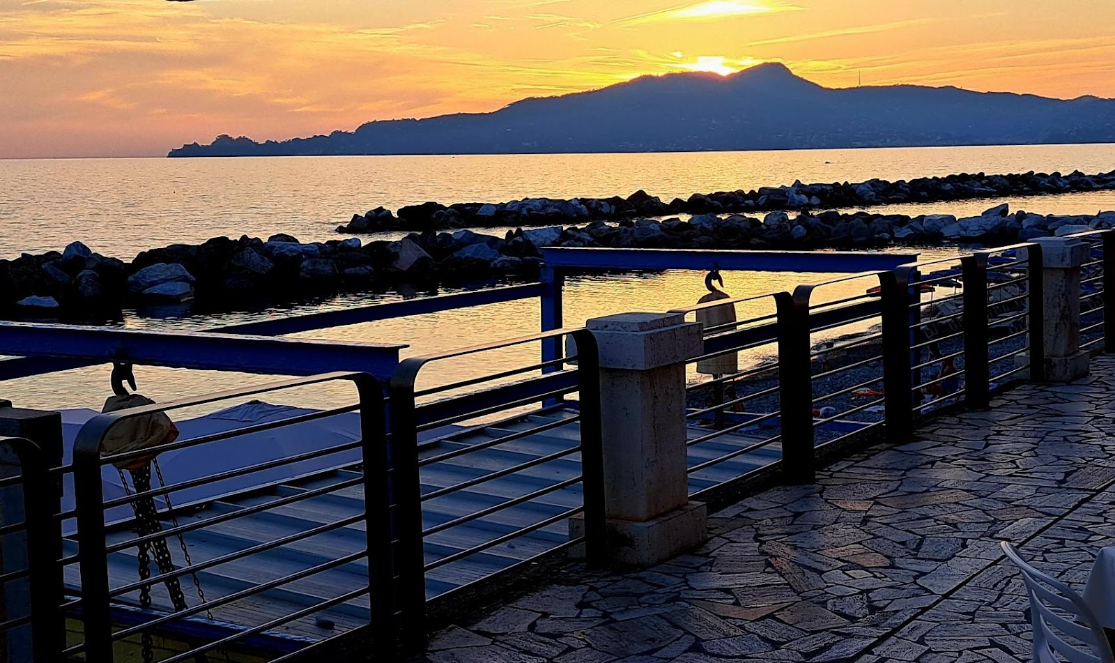 A walkway with a railing and a body of waterDescription automatically generated