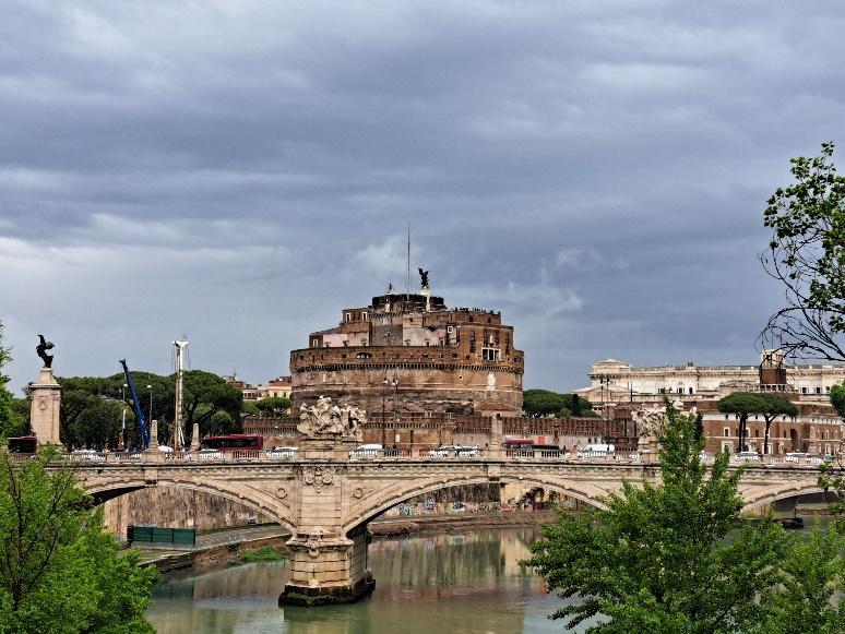 A bridge over a river with a large round buildingDescription automatically generated