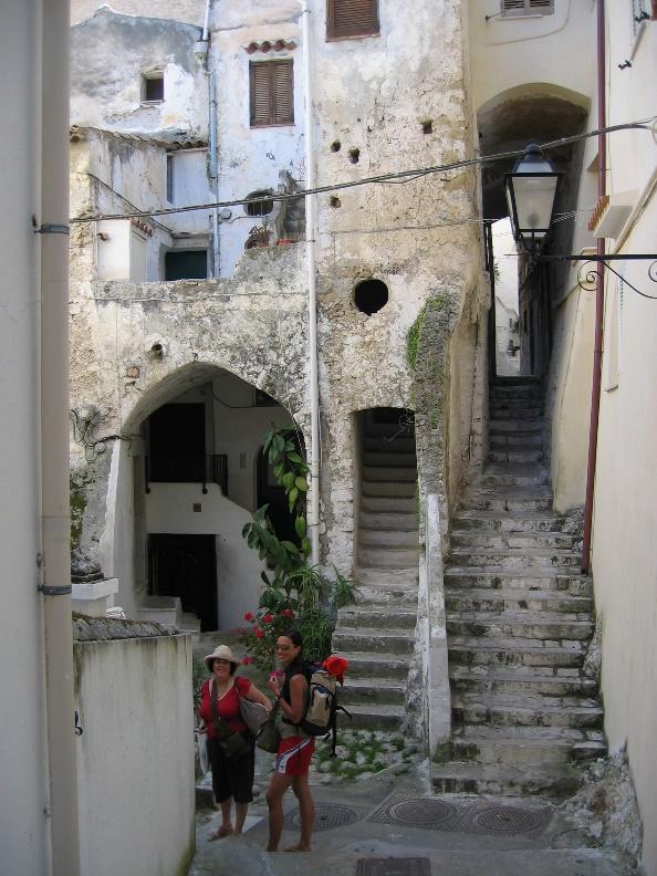A couple of people walking down a narrow streetAI-generated content may be incorrect.